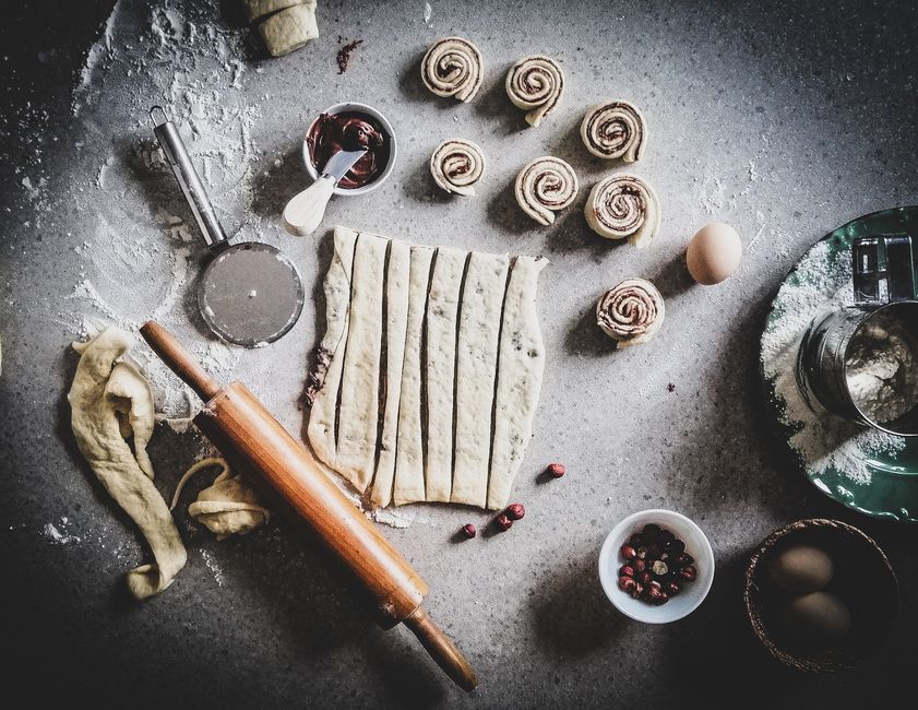 Flat lay of cinnamon buns preparation with ingredients like flour, eggs, and spices.