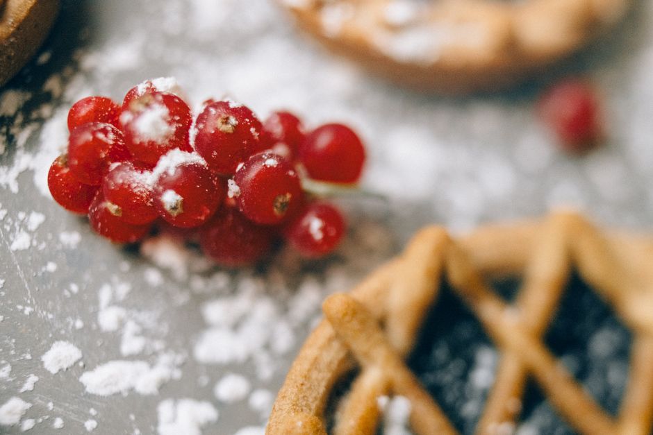 Close-up of fresh lingonberries sprinkled with sugar and pastry on a powdered surface, capturing a sweet aesthetic.